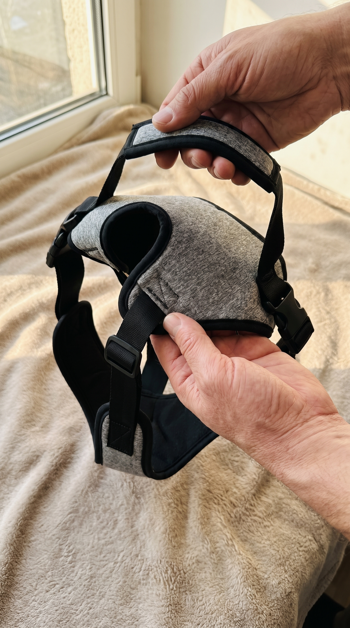 Close-up of the grey padded harness, adjustable black straps and buckles